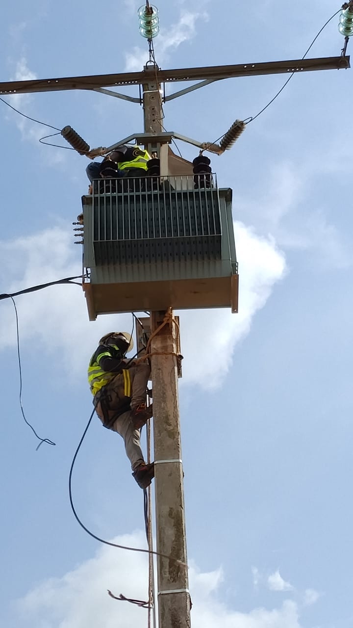 Équipe DIPRESS INTERNATIONAL installant un poste de transformation électrique en hauteur sur poteau à Abidjan