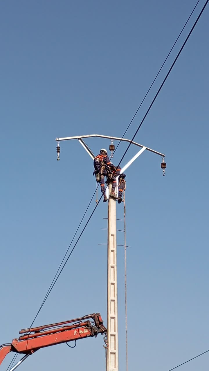 Technicien DIPRESS INTERNATIONAL sur croisillon de poteau électrique avec isolateurs suspendus