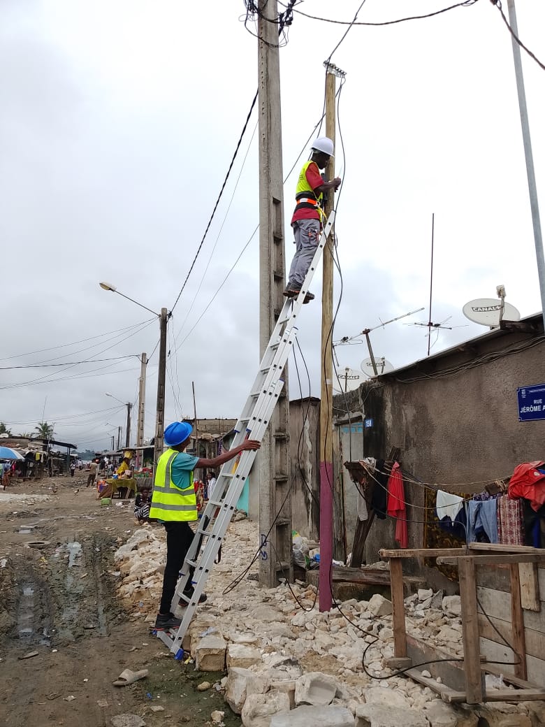 Techniciens DIPRESS effectuant un raccordement de câble télécoms sur poteau en zone urbaine à Abidjan